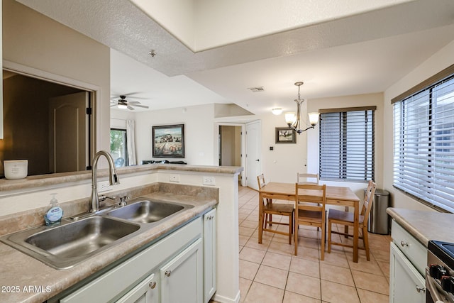 kitchen featuring pendant lighting, a textured ceiling, white cabinetry, sink, and light tile patterned flooring