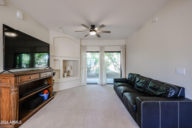 carpeted living room with ceiling fan and built in shelves