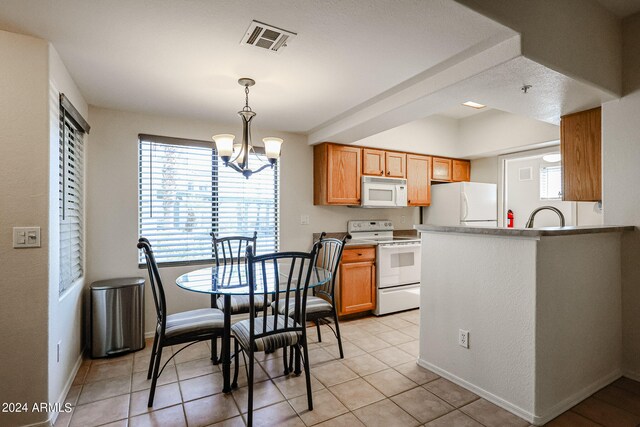 kitchen featuring white appliances, light tile patterned flooring, a chandelier, pendant lighting, and sink