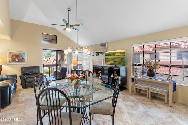 dining space featuring high vaulted ceiling, a warm lit fireplace, and a ceiling fan