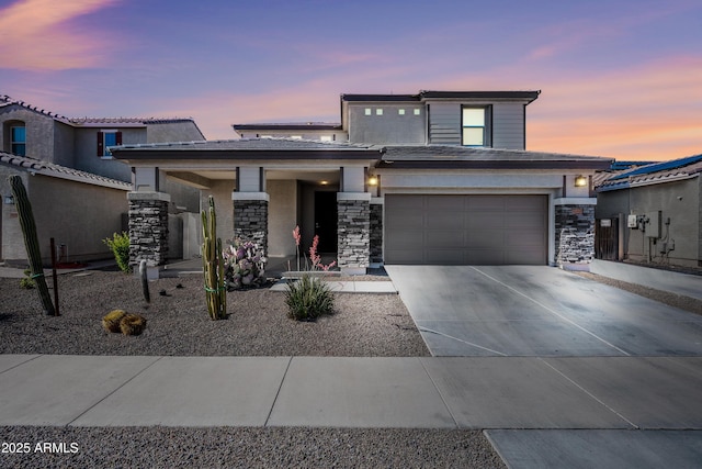 prairie-style house with concrete driveway and stone siding