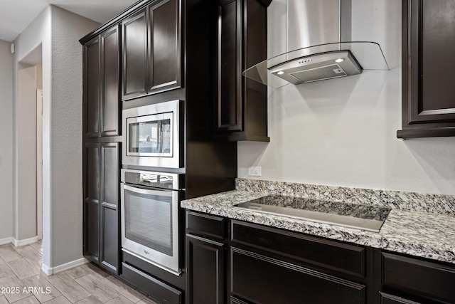kitchen featuring baseboards, appliances with stainless steel finishes, island exhaust hood, and light stone counters