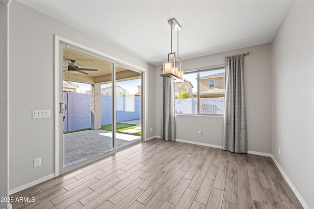 unfurnished dining area with baseboards, a ceiling fan, and wood finished floors