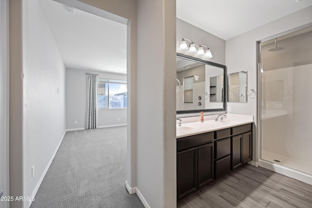 bathroom with baseboards, a sink, double vanity, and a shower stall