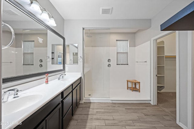 full bath with double vanity, walk in shower, a sink, and visible vents
