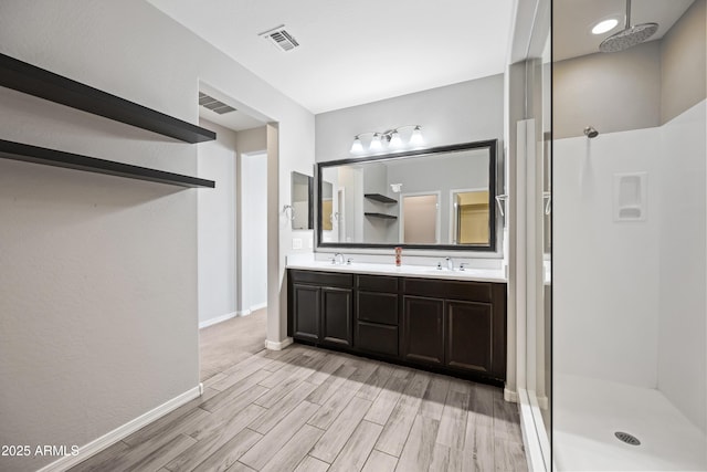 full bath featuring wood finished floors, a sink, a stall shower, and visible vents