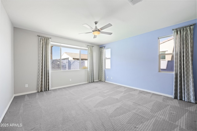 spare room with carpet floors, a ceiling fan, baseboards, and plenty of natural light
