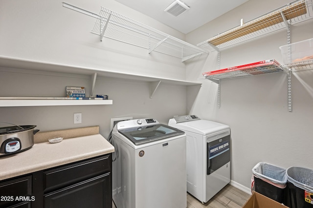 clothes washing area with separate washer and dryer, baseboards, visible vents, and light wood-style floors
