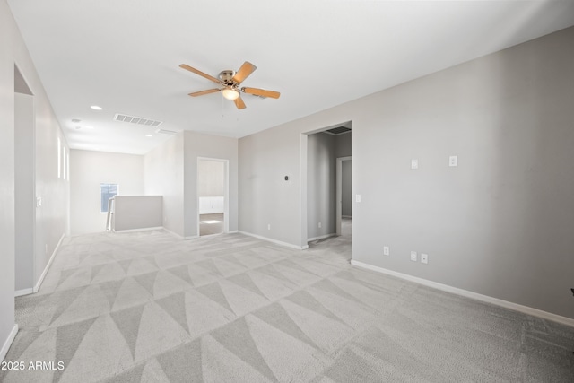 empty room with light colored carpet, ceiling fan, visible vents, and baseboards