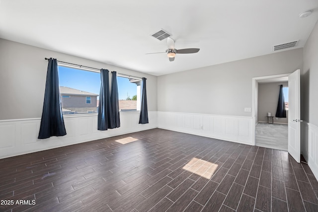 empty room with a ceiling fan, dark wood finished floors, and visible vents