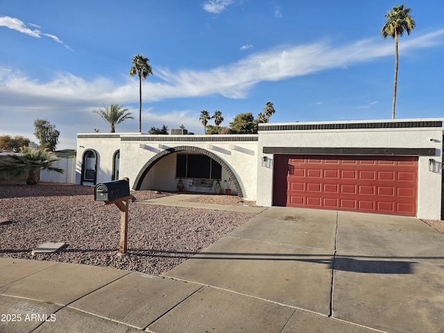 view of front of home with concrete driveway, an attached garage, and stucco siding