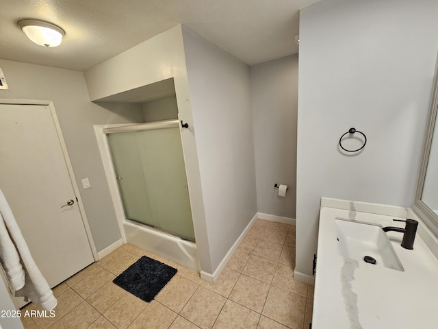 bathroom featuring vanity, tile patterned flooring, a shower with shower door, and baseboards