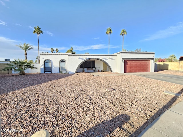 view of front of house featuring an attached garage, fence, concrete driveway, and stucco siding