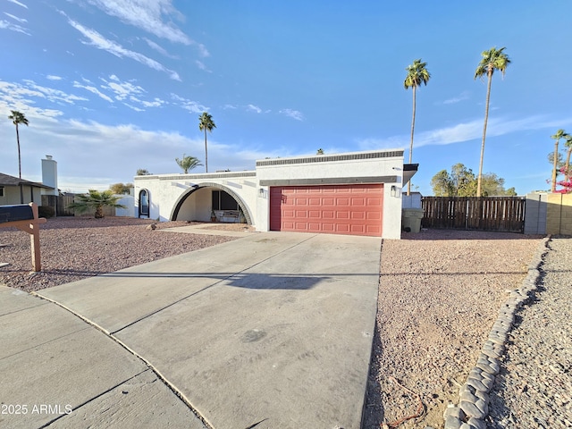 view of front of home featuring driveway, an attached garage, fence, and stucco siding