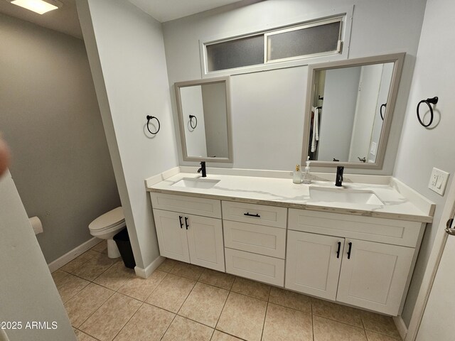 full bath featuring double vanity, a sink, toilet, and tile patterned floors