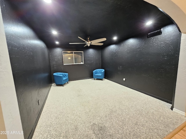 carpeted home theater with recessed lighting, arched walkways, ceiling fan, and a textured wall