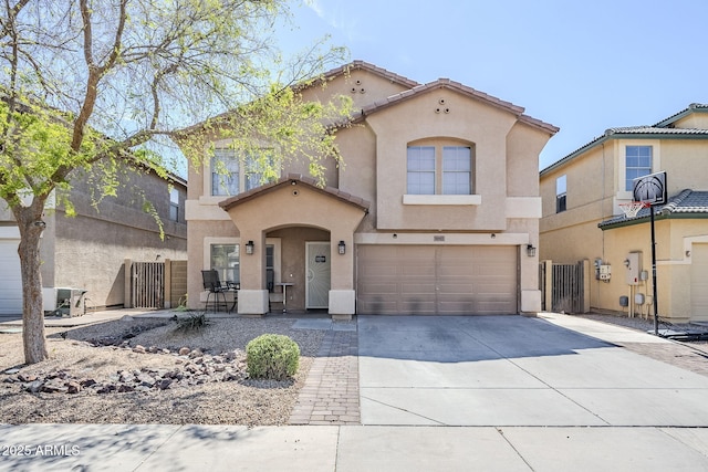 mediterranean / spanish-style home with a garage, stucco siding, fence, and concrete driveway
