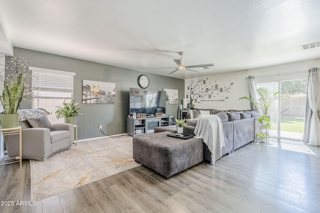 living area with a ceiling fan, visible vents, and wood finished floors