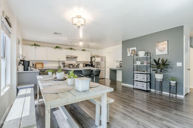 dining room with baseboards, a notable chandelier, wood finished floors, and visible vents