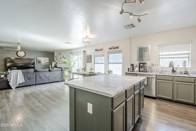 kitchen featuring visible vents, a center island, stainless steel dishwasher, gray cabinetry, and light wood finished floors