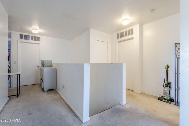 corridor with baseboards, light carpet, and visible vents