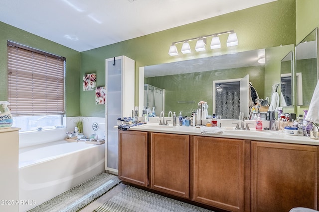 bathroom with a sink, a textured wall, double vanity, and a bath