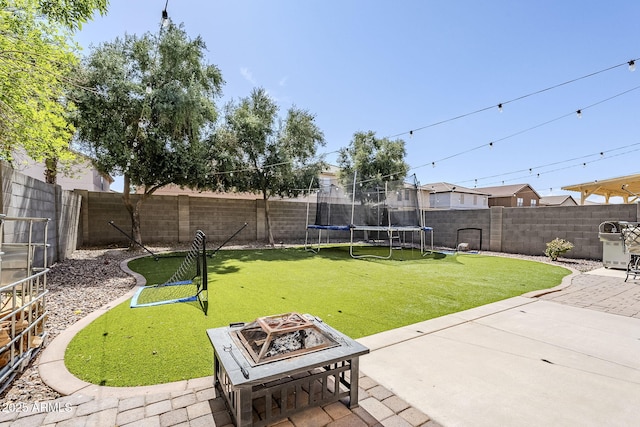 view of yard featuring a fenced backyard, a trampoline, an outdoor fire pit, and a patio