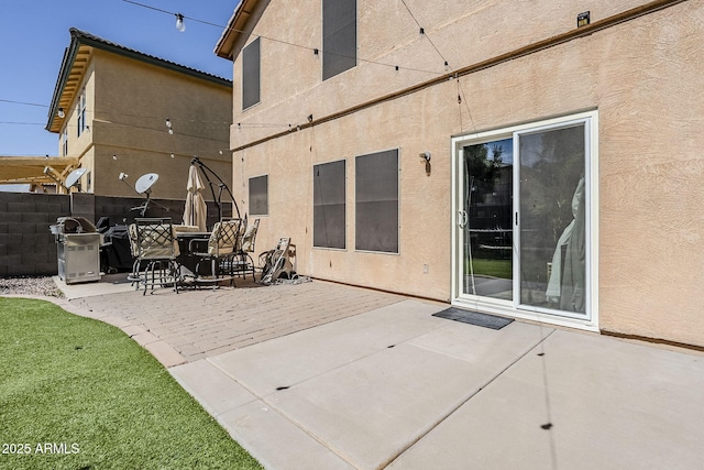 rear view of property with a patio, stucco siding, and fence