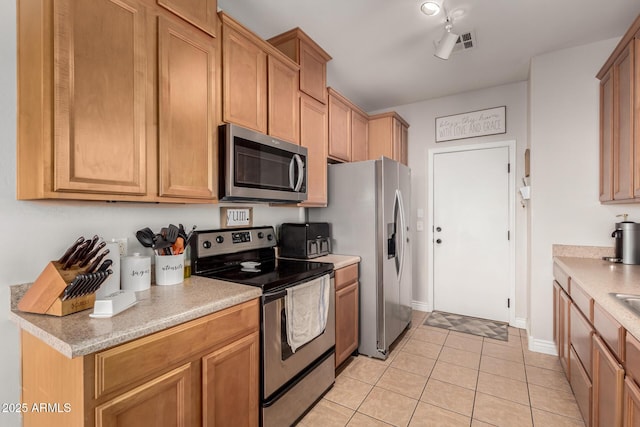 34913 N 30th Dr, Phoenix, AZ 85086 - kitchen featuring stainless steel appliances, light countertops, light tile patterned floors, baseboards, and brown cabinetry