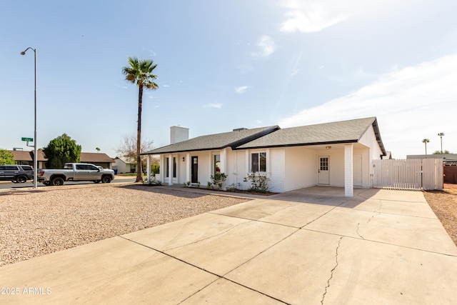 ranch-style home with driveway, fence, and a gate