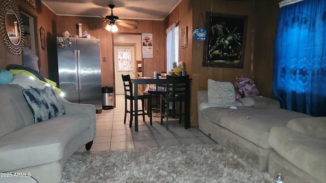 living room with light tile patterned flooring, ceiling fan, and wood walls