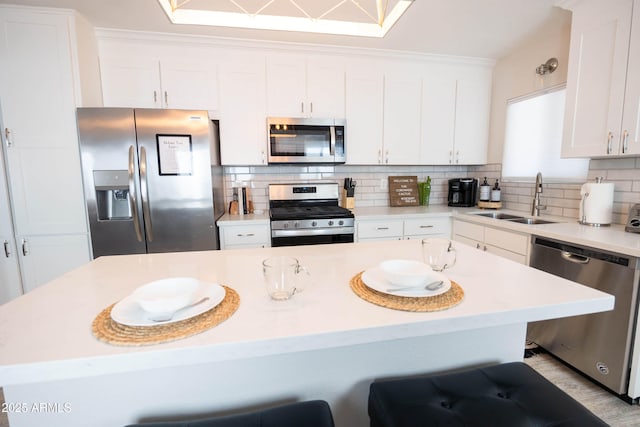 1513 E Sheridan St, Phoenix, AZ 85006 - kitchen featuring appliances with stainless steel finishes, a sink, a kitchen breakfast bar, tasteful backsplash, and white cabinets