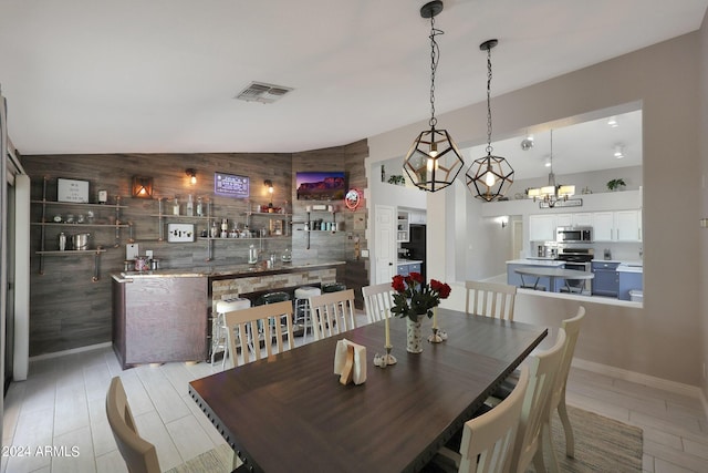 dining room featuring vaulted ceiling and wood walls