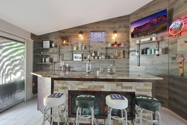 bar featuring lofted ceiling and wooden walls