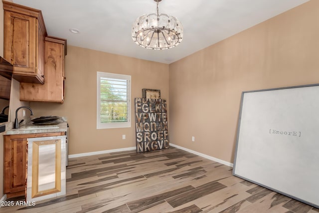 kitchen featuring hanging light fixtures, sink, an inviting chandelier, and light hardwood / wood-style floors