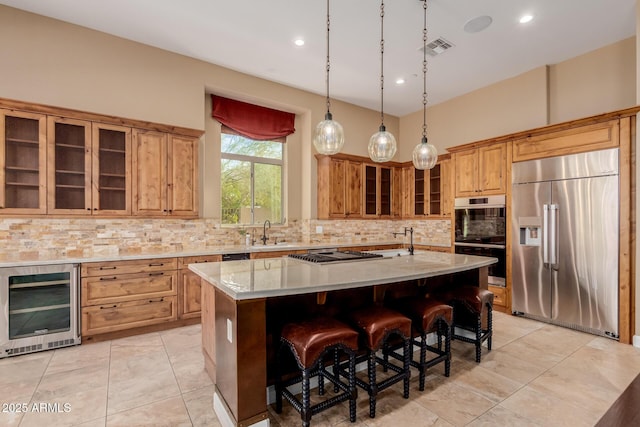 kitchen with wine cooler, appliances with stainless steel finishes, light stone countertops, and a kitchen island