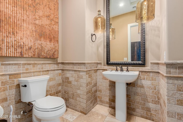 bathroom featuring tile walls, sink, and toilet