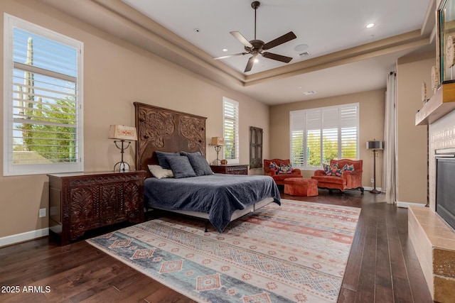 bedroom with a tray ceiling, dark wood-type flooring, and ceiling fan