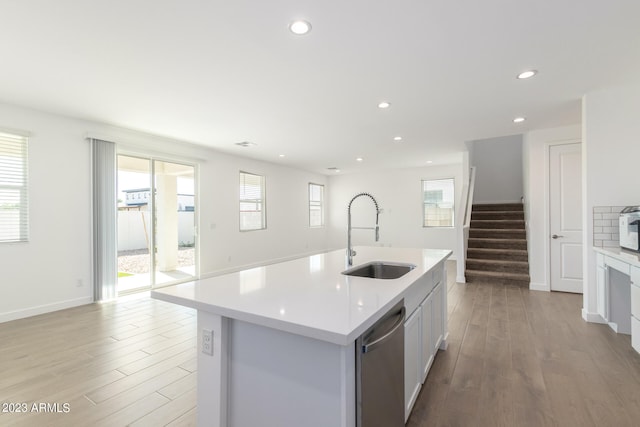 kitchen with a kitchen island with sink, light hardwood / wood-style flooring, white cabinetry, sink, and dishwasher