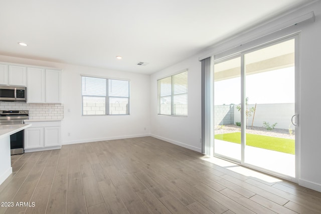 kitchen with tasteful backsplash, light hardwood / wood-style floors, stainless steel appliances, and white cabinets