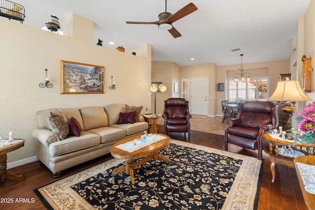 living room with ceiling fan with notable chandelier and dark hardwood / wood-style flooring