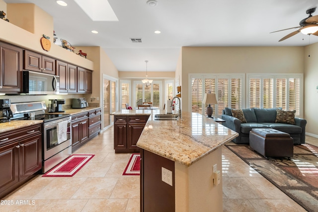 kitchen with sink, a healthy amount of sunlight, an island with sink, decorative light fixtures, and stainless steel range with electric stovetop