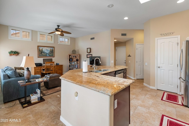 kitchen featuring sink, ceiling fan, light stone countertops, an island with sink, and appliances with stainless steel finishes