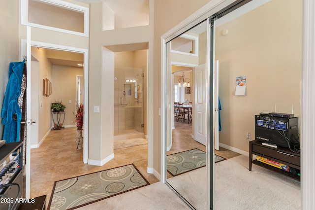 bathroom with tile patterned floors, a shower with door, a high ceiling, and a chandelier