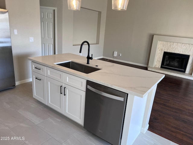 kitchen featuring a sink, stainless steel appliances, light stone countertops, and pendant lighting