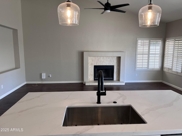 interior space with light stone countertops, dark wood-style flooring, a sink, hanging light fixtures, and open floor plan