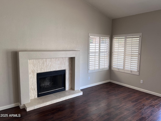 unfurnished living room with vaulted ceiling, baseboards, and wood finished floors