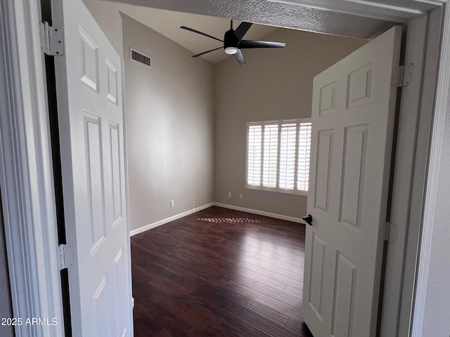 unfurnished bedroom featuring dark wood finished floors, baseboards, visible vents, and ceiling fan