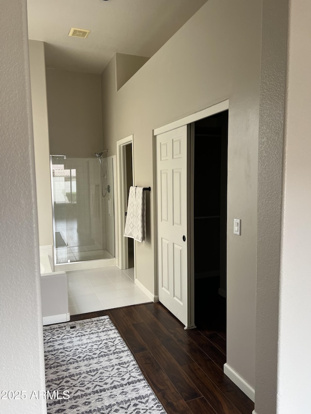 full bath with wood finished floors, a shower, baseboards, and visible vents