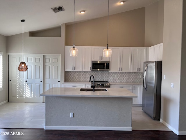 kitchen with visible vents, backsplash, appliances with stainless steel finishes, white cabinetry, and a sink